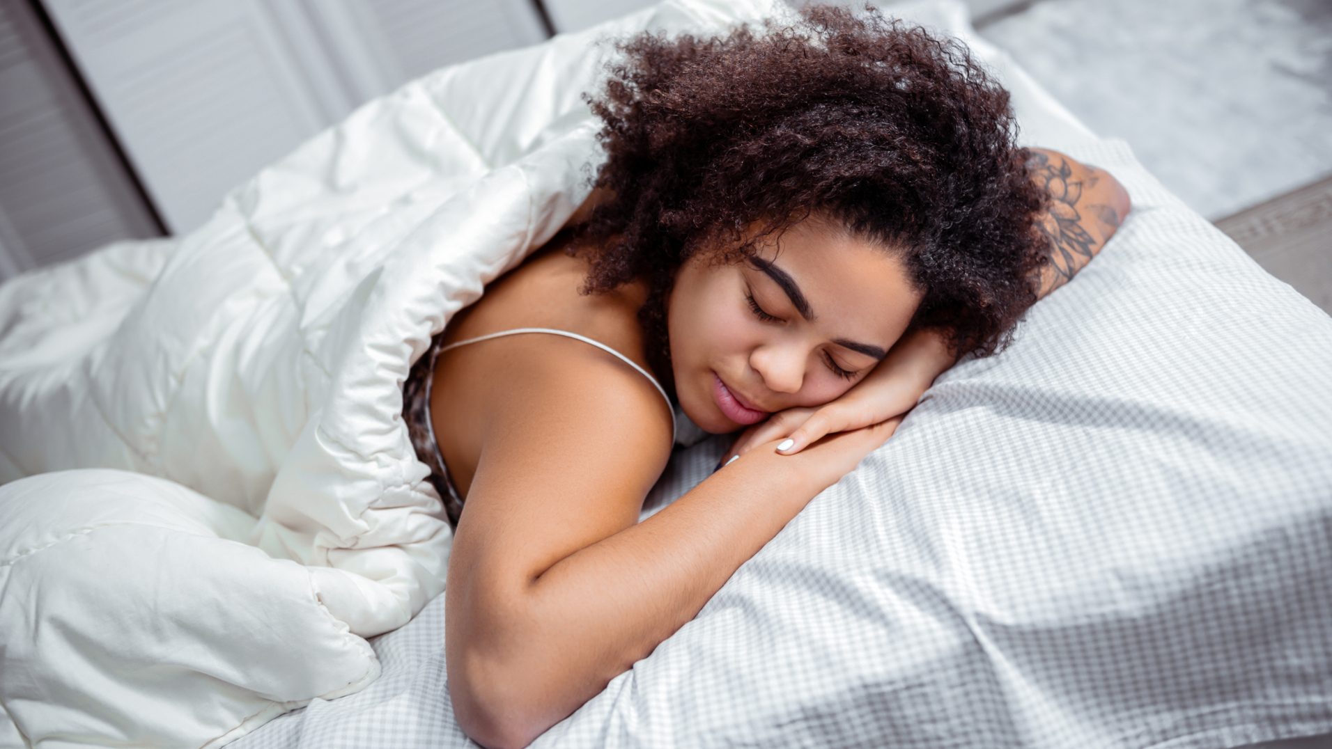 The 10-3-2-1-0 Sleep Rule: Does This Simple Formula Guarantee a Better Night's Rest? curly short haired lady putting head down on connected hands